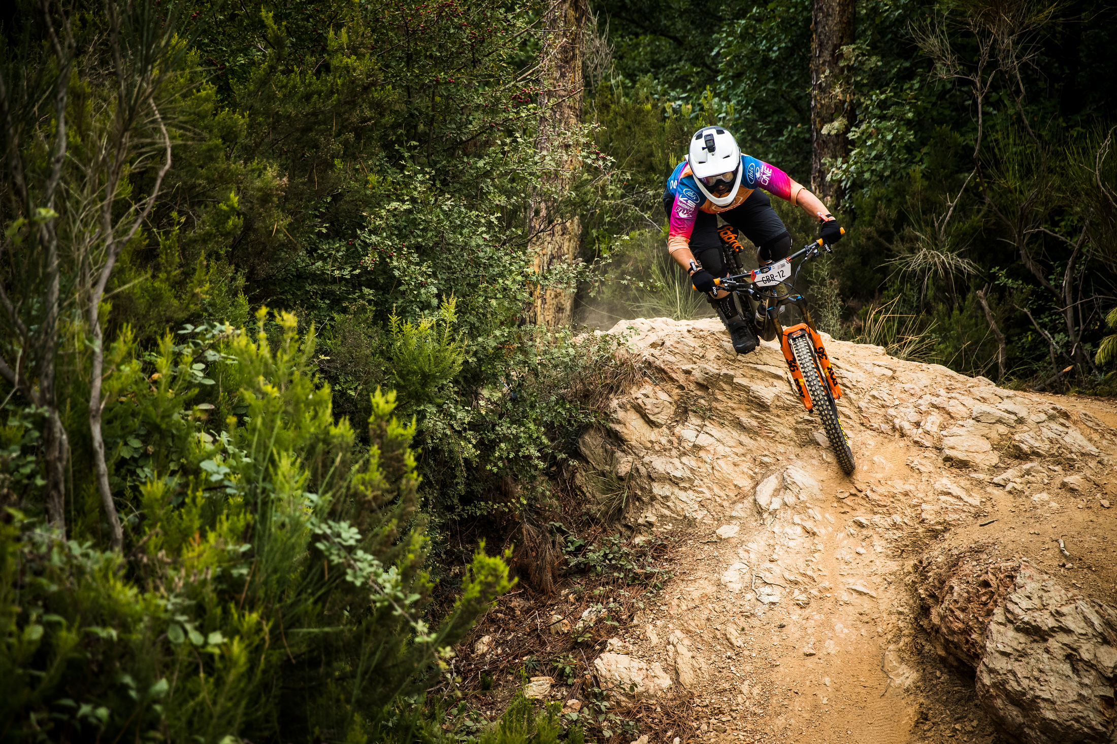 Bex Barona rolls down the back side of a boulder in her tie-dye Ibis jersey.